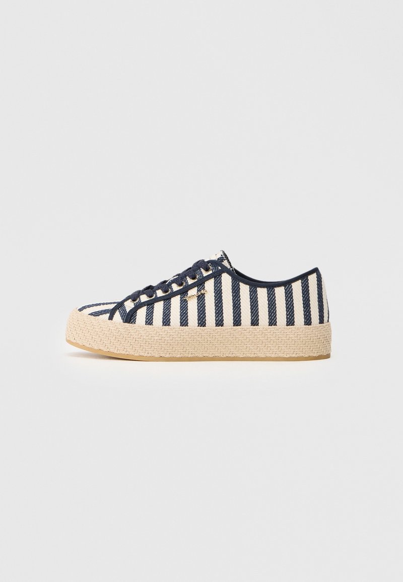 Basket basse avec des rayures verticales bleu marine et blanches, des lacets bleu marine et une semelle beige épaisse et texturée, vue de côté sur un fond clair.