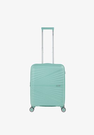 Maleta verde menta con una superficie texturizada y estriada, mango retráctil y cuatro ruedas dobles para facilitar el movimiento. Diseño compacto.