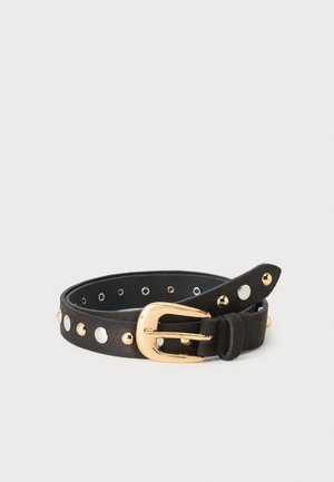 Ceinture en cuir noir avec des clous ronds alternés en or et argent et une boucle dorée brillante, enroulée sur un fond clair uni.