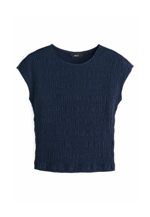 Tumszils īsroku tops no faktūras auduma ar vaļēju piegriezumu un apaļu kakla izgriezumu. Visā virsmā ir horizontālas krokojumu līnijas.