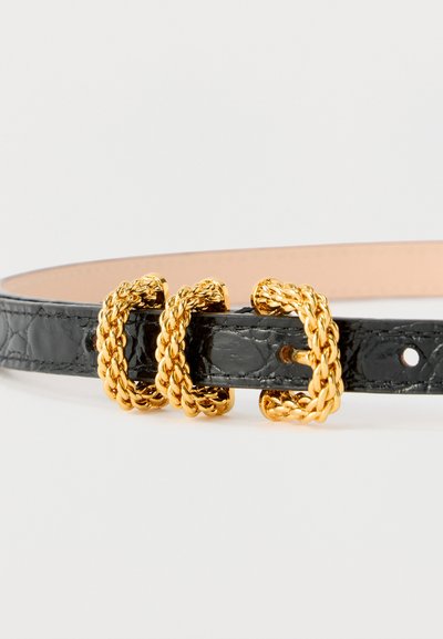 Fekete bőrszíj három fonott arany fémcsattal, laposan fehér háttér előtt elhelyezve.