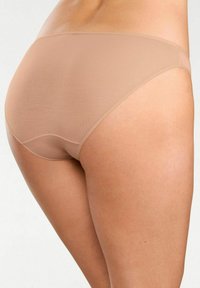 Perizomi hipster beige senza cuciture realizzati in un morbido tessuto elasticizzato. Presentano una superficie liscia opaca con una linea semplice e senza cuciture visibili.