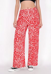 Rood-witte patroon wijde broek met een elastische tailleband, voorzien van een draaiend abstract ontwerp en een lichtgewicht stof.