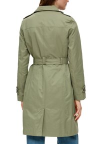 Oliwkowy trencz z paskiem w talii, długimi rękawami i klasycznym kołnierzem. Posiada guziki na naramiennikach oraz wentylację z tyłu.