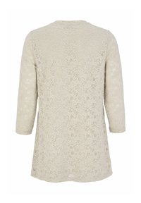 Lace top i lys beige med trekvartærmer. Har et indviklet blomstermønster og en rund halsudskæring, der giver et struktureret udseende.