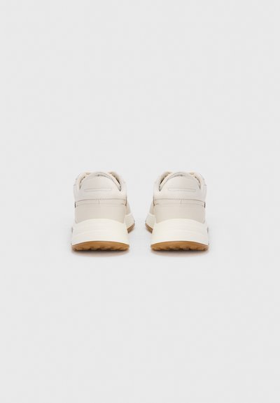 Μπεζ αθλητικά παπούτσια με λείο δερμάτινο επάνω μέρος, στρογγυλεμένο σχήμα, επενδυμένο περιμετρικά και υφασμένο καουτσούκ σόλα για πρόσφυση.