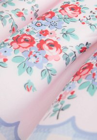 Koguva heleroosa kangas lillemustriga, millel on punased, roosad ja sinised lilled ning rohelised lehed.