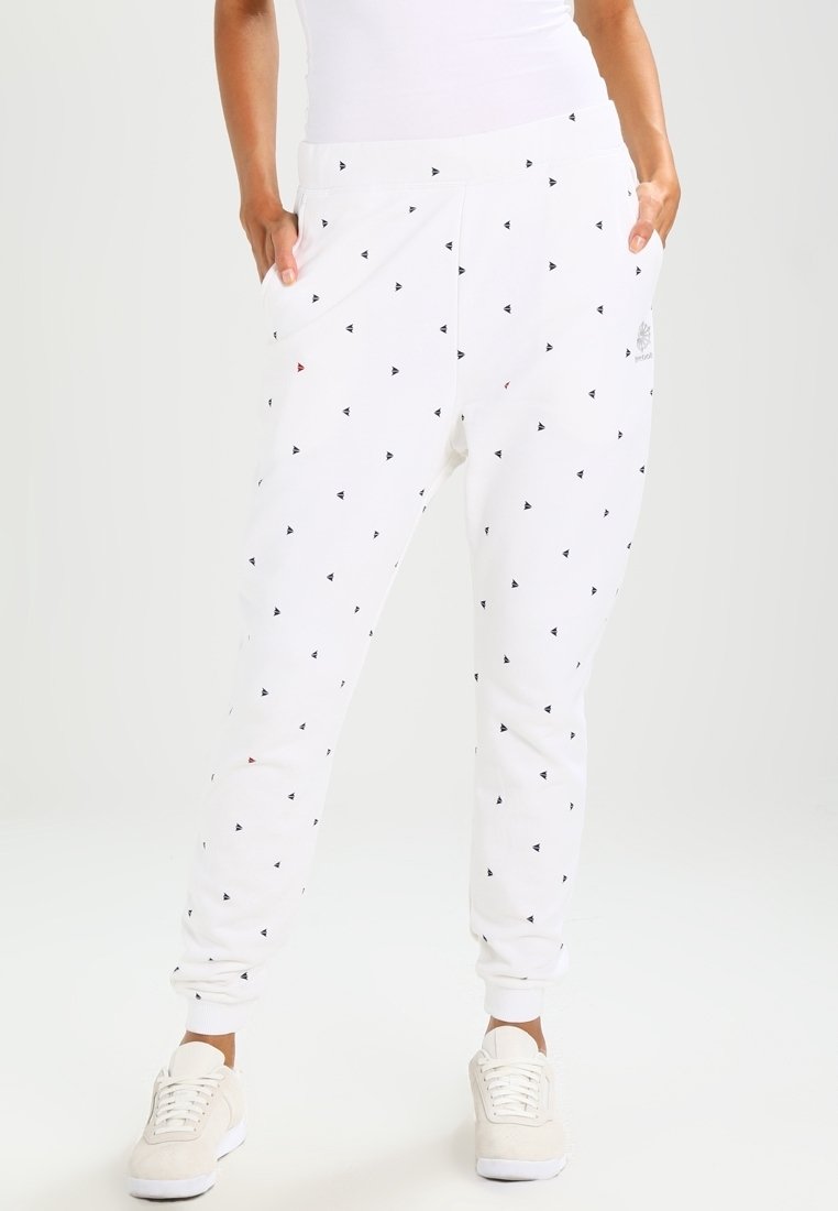 Vita träningsbyxor med lös passform, prydda med ett mönster av små svarta och röda trianglar. Elastisk midja och muddar. Slät tygtextur.