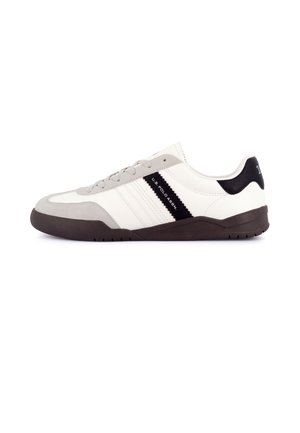 Baskets basses blanches et grises avec semelle noire et patch au talon, bande noire latérale avec logo U.S. Polo Assn., et lacets gris assortis.