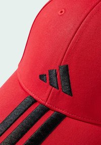 Gorra de béisbol roja con franjas negras en contraste y un logo negro bordado. El tejido es suave, con una forma estructurada y visera redondeada.