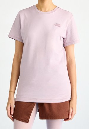 T-shirt en coton lavande clair avec un col rond, des manches courtes et un petit logo brodé sur la poitrine. Texture lisse et coupe décontractée.