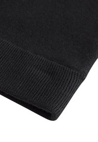 Manica di un maglione nero lavorato a maglia, caratterizzata da una texture liscia, finitura a costine e orlo ripiegato. Vista ravvicinata, che mette in evidenza i dettagli del materiale.