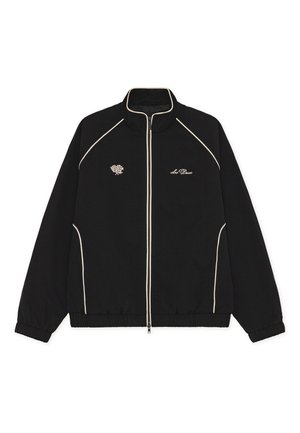 Schwarze Zip-Jacke mit hohem Kragen, weißer Paspelierung und Rosenstickerei auf der linken Brust. Weicher Stoff und elastische Bündchen am Saum.