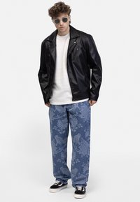 Black leather biker jacket, white textured sweater, blue patterned denim pants, and black sneakers. Accented with round sunglasses.
