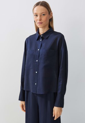 Navy blue button-up shirt with a structured collar, long sleeves, and two front pockets. Made from a smooth, slightly reflective fabric.