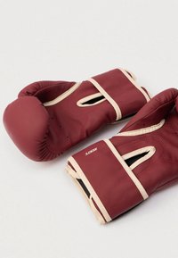 Bordové boxerské rukavice s hladkým syntetickým povrchom, svetlobéžovými akcentmi a vetracími otvormi, s bezpečným suchým zipsom.