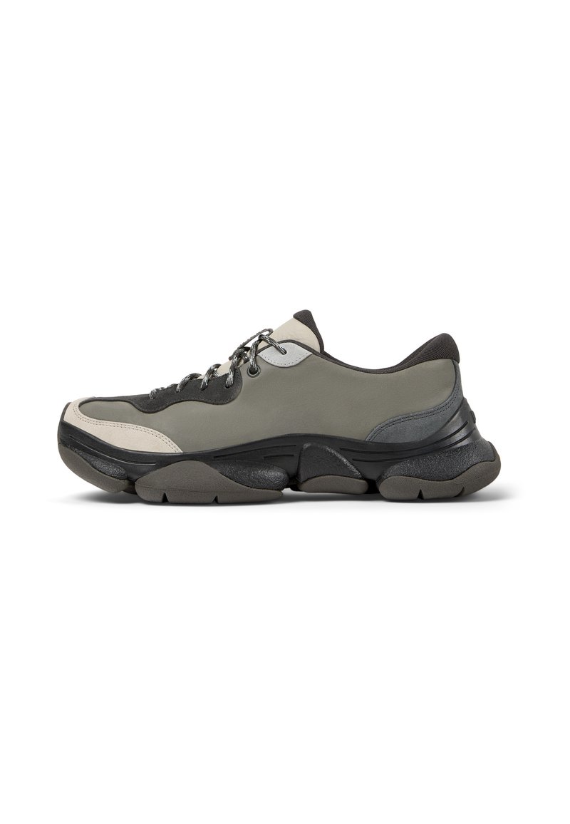 Herren Sneaker, mit einer Mischung aus olivgrünem und schwarzem Material, dicker Sohle, strukturierten Akzenten und einem Schnürdesign.