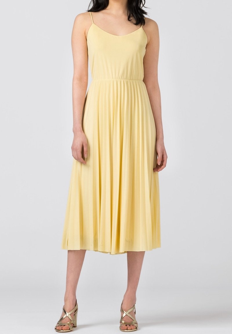 Gul midi-klänning med tunna axelband, rynkad midja och flödande plisserad kjol. Slätt tyg, elegant snitt och mjuka draperingsdetaljer.