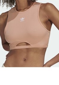 Żeberkowy top z krótkim rękawem w miękkim różowym kolorze z okrągłym dekoltem i wycięciem na dole. Posiada białe logo Adidas na piersi.