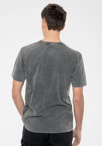 Short-sleeve grey t-shirt made of soft cotton, featuring a washed texture, crew neckline, and subtle stitching details on edges.