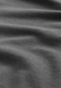Tejido gris oscuro con una textura suave, que presenta sutiles olas y pliegues. El material parece suave y duradero, adecuado para varios usos.