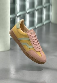 Flerfarget sneaker med overdel i semsket skinn i gult, rosa og grønt, med en teksturert gummisåle og fremtredende merkevare på tungen.