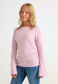 Lichtroze lange mouwen shirt met een geweven bloemenpatroon en een vierkante halslijn. Gecombineerd met blauwe dennenjeans.