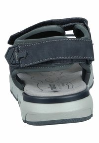 Ciemnoniebieskie obuwie z regulowanymi paskami, wyściełaną wkładką i teksturowaną podeszwą. Posiada kontrastujące przeszycia i płaski fason.