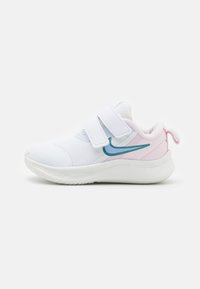 Zapatilla deportiva blanca con parte superior de malla, dos correas de Velcro y acentos en teal y rosa. Suela redondeada para soporte y agarre.