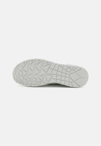 White athletic shoe sole with a textured pattern of triangles and lines, designed for traction and durability. Flat, rubber material.