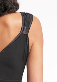 Musta hihaton vaate, jossa on sileä ja kiiltävä pinta. Ominaisuuksiin kuuluu tyylikäs muotoilu, paksut olkaimet ja hienovarainen satiiniyksityiskohta yhdessä olkaimessa.