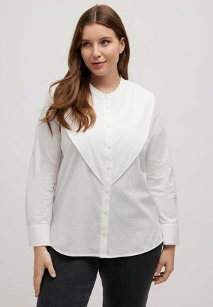Blusa bianca a maniche lunghe con un colletto sovrapposto distintivo, chiusura con bottoni e un tessuto morbido e leggero.
