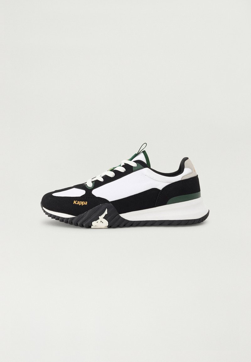 Zapatilla deportiva en blanco y negro con acentos verdes y grises, que presenta una suela texturizada, un diseño de cordones y un logo de marca en el costado.