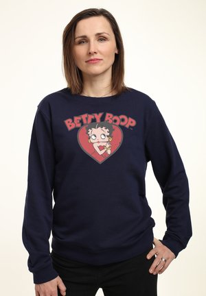 Marineblå sweatshirt med et Betty Boop grafisk motiv inden i et hjerte. Blødt stof, lange ærmer, ribstrikkede manchetter og nederkant.