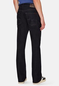 Jeans blu scuro con un design a gamba dritta, tasche posteriori, cuciture a contrasto e un’etichetta della vita testurizzata.