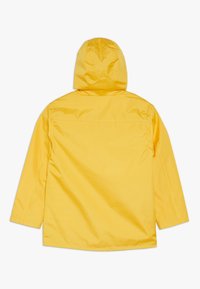 Chaqueta impermeable amarilla con capucha, que presenta una textura suave y un corte recto. Vista trasera muestra detalles mínimos y sin herrajes visibles.