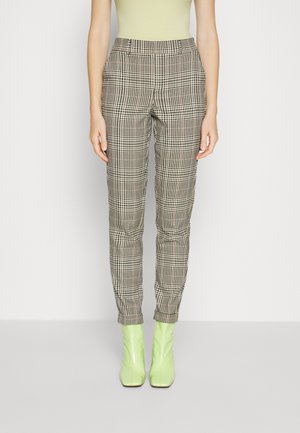 Pantalons à carreaux dans des tons neutres avec une coupe slim, dotés d'une taille élastique. Associés à des bottines vertes brillantes.