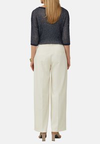 Marineblauwe gebreide cropped top met driekwart mouwen, gecombineerd met hooggetailleerde ivoorkleurige wijde broek en chunky beige blokhak sandalen.