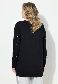 Maglietta nera a maniche lunghe con una vestibilità morbida, caratterizzata da dettagli in perle lungo le maniche e un colletto rotondo. Tessuto morbido con una superficie liscia.