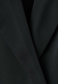 Czarna marynarka z tkaniny o gładkiej fakturze i wyraźnych klapach, prezentująca dopasowany krój i czyste linie.