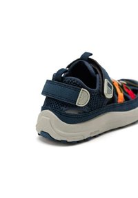 Sandalo in tessuto blu navy con cinturini multicolori, chiusura posteriore con velcro e suola in gomma grigia chiara con battistrada testurizzato.