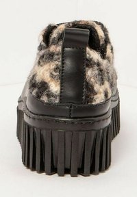 Zapatos de plataforma negros con una parte superior de lana texturizada que presenta un patrón en tonos beige y marrón. La parte trasera tiene una tira para facilitar el calzado y un diseño de flecos en la suela.