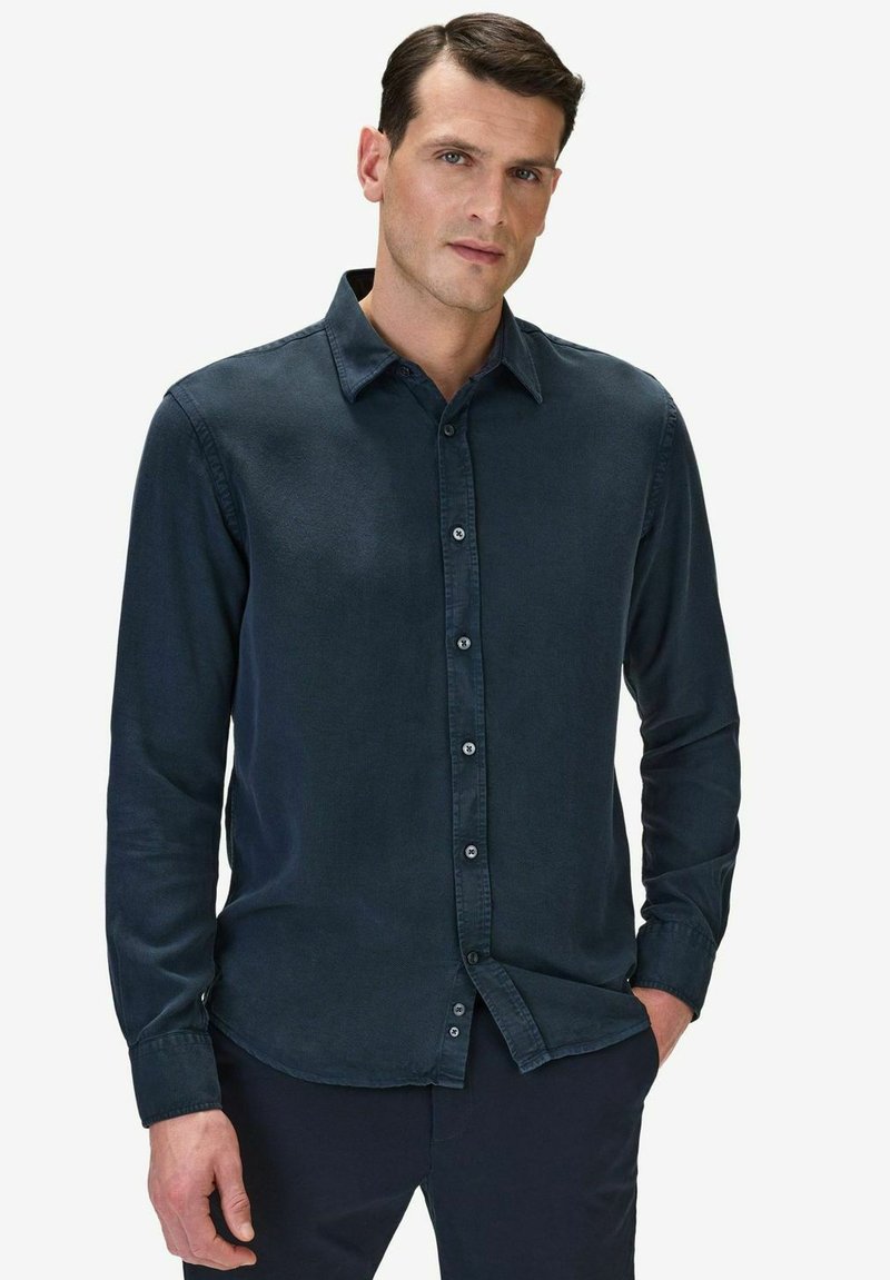 Mörkblå, långärmad skjorta med knappar tillverkad av mjukt tyg. Har en klassisk krage, framknappar och en avslappnad passform med rundad nederkant.