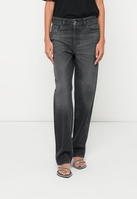 Augsta vidukļa, taisnas melnas džinsa bikses ar smalku izbalējušu apdari, metāla pogu aizdari un klasisku piecu kabatu dizainu.