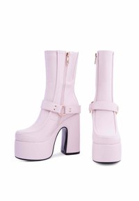 Stivaletti alla caviglia in ecopelle rosa con punta quadrata, cerniera laterale e dettaglio della fibbia. Tacchi neri robusti per stabilità.