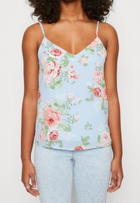 Světle modrý květinový top s tenkými ramínky, zdobený růžovými a zelenými vzory růží, s V-výstřihem a hladkým, lehkým materiálem.