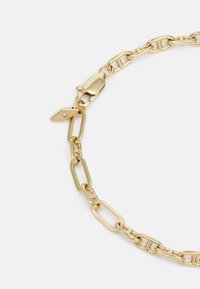 Bracciale in metallo dorato con maglie allungate, chiusura e un piccolo charm decorativo a forma triangolare con una singola pietra preziosa.