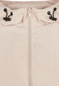 Lys rosa zip-up jakke med hette, med svarte snorer og en glatt, lett skinnende stofftekstur.