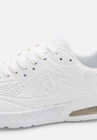 Witte sportschoen met een gestructureerde synthetische bovenkant, voorzien van perforaties, veters en een verhoogde logoaccent. Heldere luchtunit in de zool.