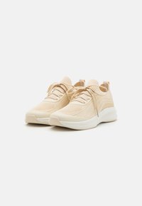 Lys beige treningssko med en teksturert strikkoverdel, rund tå, snøring og en polstret hvit såle.